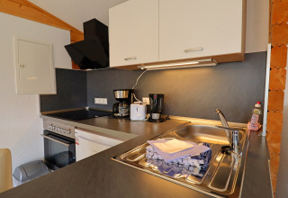 Modern kitchen at Räuberkuhle Koserow in Germany with appliances, sink, dish soap, and folded towels.