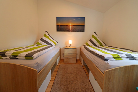 Cozy twin room in Räuberkuhle Koserow, Germany, with striped bedding, wooden beds, and wall art.