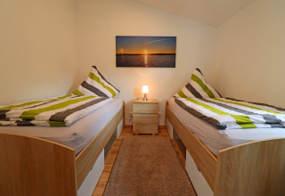 Cozy twin room in Räuberkuhle Koserow, Germany, with striped bedding, wooden beds, and wall art.