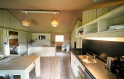 Interno di una spaziosa tenda safari con cucina moderna, tavolo da pranzo, salotto e letti a castello.