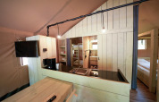 Interior de una tienda safari con muebles de madera, cocina, literas y dormitorio acogedor.
