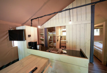 Interior de una tienda safari con muebles de madera, cocina, literas y dormitorio acogedor.