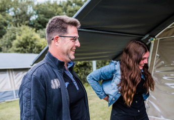 Twee mensen lachen samen voor een safaritent op Resort Echternacherbrück 1 in Duitsland.