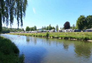 Vue sur la rivière au Resort Echternacherbrück 2 en Allemagne, avec caravanes, arbres et nature verdoyante