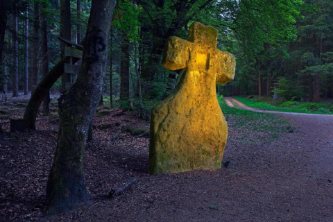 Verlicht stenen kruis naast een bosweg nabij Resort Echternacherbrück 2 in Duitsland.