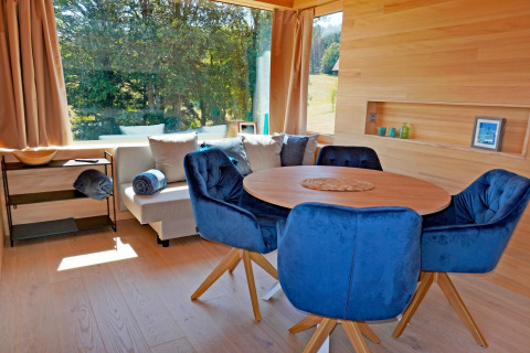 Bright, modern living area in Haus Wasser cabin, Germany, featuring blue chairs and large windows.