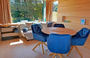 Bright, modern living area in Haus Wasser cabin, Germany, featuring blue chairs and large windows.