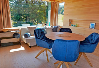 Bright, modern living area in Haus Wasser cabin, Germany, featuring blue chairs and large windows.
