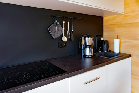 Modern kitchen countertop at Haus Wasser in Germany featuring coffee maker, stove, and hanging utensils.