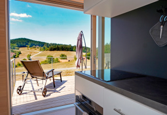 View from the kitchen at Haus Wasser, Germany, overlooking a sunny terrace and scenic rural hills.