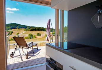 View from the kitchen at Haus Wasser, Germany, overlooking a sunny terrace and scenic rural hills.