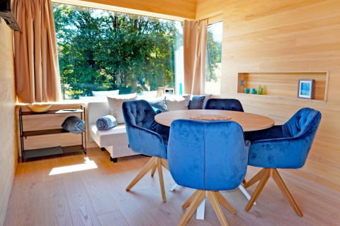 Modern living room at Haus Wasser, Germany, featuring blue chairs, wood table, and large scenic window views.