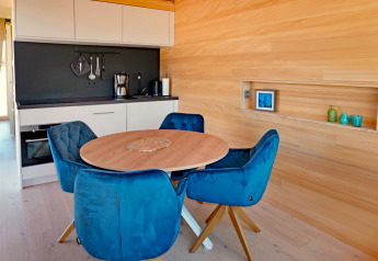 Modern kitchen and dining area in a wooden cabin, featuring blue chairs at Haus Wasser in Germany.