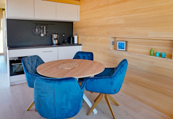 Modern kitchen and dining area in a wooden cabin, featuring blue chairs at Haus Wasser in Germany.