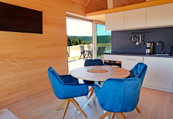 Contemporary cabin interior at Haus Wasser in Germany with blue chairs, round table, and kitchen.