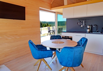 Contemporary cabin interior at Haus Wasser in Germany with blue chairs, round table, and kitchen.