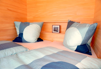Knus bed met blauwe dekens in een houten hut genaamd Haus Wasser in Duitsland.
