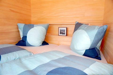 Cozy bed with blue bedding and pillows in a wooden cabin called Haus Wasser in Germany.