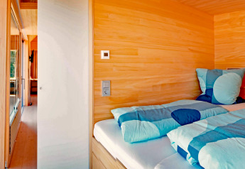 Cozy wooden bedroom with blue bedding in Haus Wasser cabin, a scenic retreat in Germany.