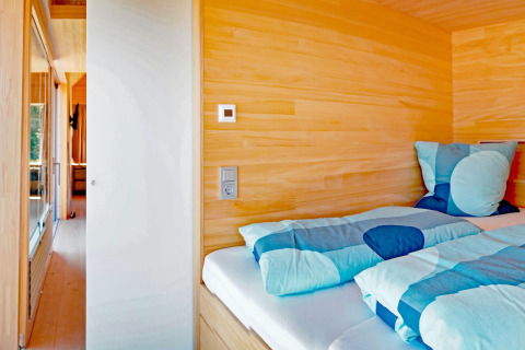 Cozy wooden bedroom with blue bedding in Haus Wasser cabin, a scenic retreat in Germany.