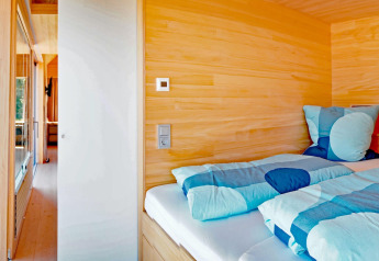 Cozy wooden bedroom with blue bedding in Haus Wasser cabin, a scenic retreat in Germany.