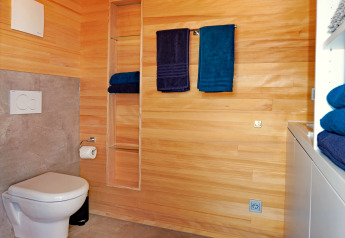 Modern wooden bathroom at Haus Wasser, Germany, featuring wall-mounted toilet and blue towels.