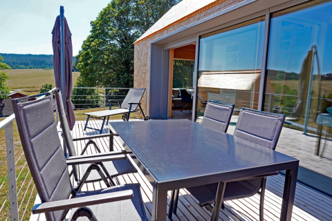 Outdoor terrace at Haus Wasser, Germany, featuring dining table, chairs, and a scenic natural view.