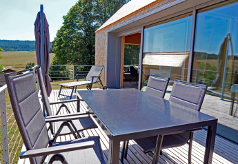Outdoor terrace at Haus Wasser, Germany, featuring dining table, chairs, and a scenic natural view.