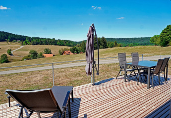 Uitzicht vanaf het terras van de Haus Wasser cabin in Duitsland met buitenmeubilair en heuvels.