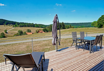 View from the terrace at Haus Wasser cabin in Germany with outdoor furniture and scenic hills.