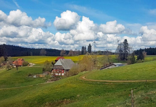 Scenic countryside at Haus Wasser, Germany, with green hills, farmhouses, wind turbines, and a blue sky.