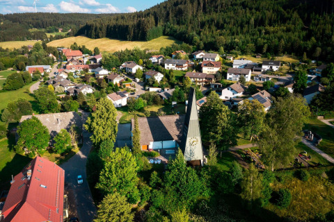 Aerial view of Haus Wasser cabin in Germany, surrounded by a scenic village and lush green forests.