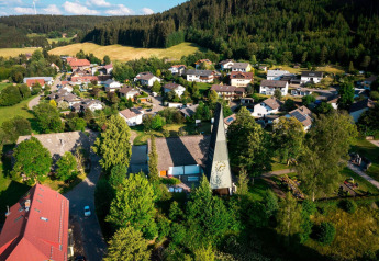 Aerial view of Haus Wasser cabin in Germany, surrounded by a scenic village and lush green forests.