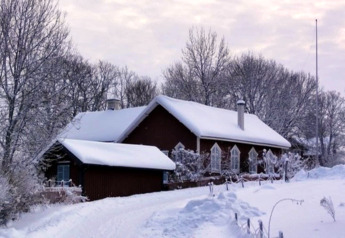 Sneeuwbedekte hut genaamd Haus Wasser in Duitsland, omringd door kale bomen en een winterlandschap.