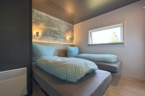 Dormitorio moderno en Holiday village SEEBLICK Tiny Chalet con dos camas individuales y almohadas grandes.