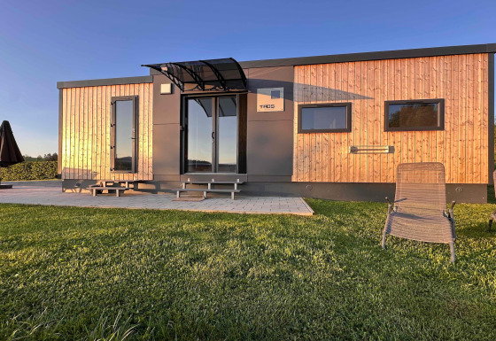 Modernes Tiny House mit Holzfassade am Holiday village SEEBLICK am Eixendorfer See im Sonnenschein.