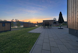 Udsigt over små chaleter ved søen Eixendorfer i Tyskland ved solopgang, med terrasse og udendørs møbler.