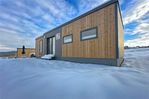 Modern tiny house in Holiday Village SEEBLICK aan het Eixendorfermeer, Duitsland, omgeven door sneeuw.