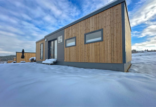 Modern tiny house bij Holiday Village SEEBLICK aan de Eixendorfer See, Duitsland, omgeven door sneeuw.