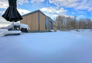 Tiny house in legno con terrazza innevata al villaggio Holiday SEEBLICK, lago Eixendorfer, Germania.