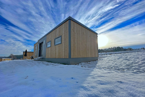 Kleines Holzhaus im Schnee am Ferienpark SEEBLICK am Eixendorfer See mit weitem Himmel, Deutschland