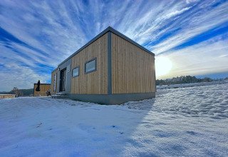 Kleines Holzhaus im Schnee am Ferienpark SEEBLICK am Eixendorfer See mit weitem Himmel, Deutschland