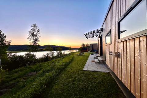 Sunset view at Holiday village SEEBLICK - Tiny Chalet on Lake Eixendorfer in Germany, overlooking water and hills.