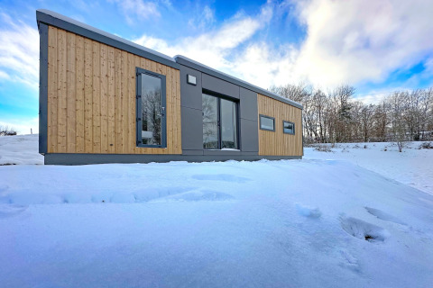 Moderne tiny house 'SEEBLICK - Tiny Chalet on Lake Eixendorfer' i sne, omgivet af vinterskov i Tyskland.