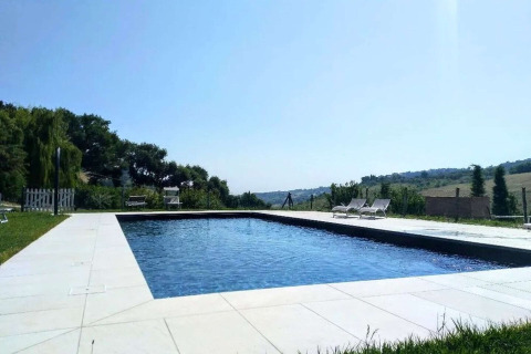Swimming pool with lounge chairs at the Tenda Luxury 2 safari tent in Italy, surrounded by scenic hills.