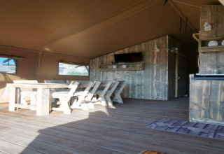 Interno in legno della tenda safari 'Tenda 1' in Italia con tavolo da pranzo rustico e sedie.