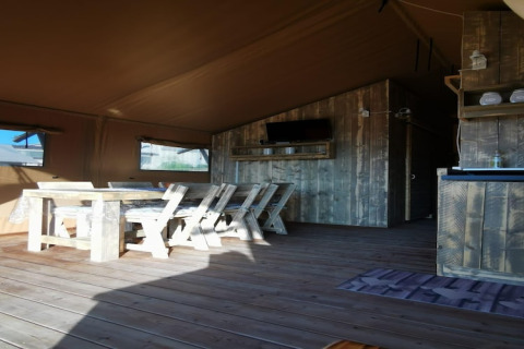 Rustiek houten interieur in safaritent 'Tenda 1' in Italië, met eethoek en landelijke uitstraling.