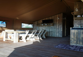 Rustiek houten interieur in safaritent 'Tenda 1' in Italië, met eethoek en landelijke uitstraling.