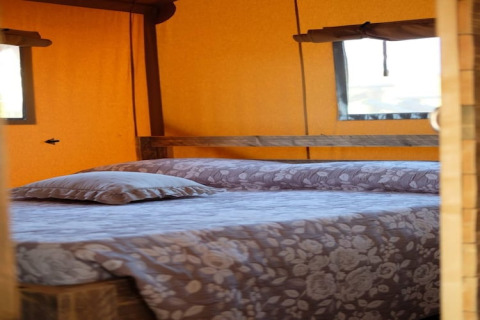 Binnenaanzicht van een tweepersoonsbed met bloemenbeddengoed in safaritent Tenda 1 in Italië.