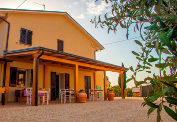 Buitenaanzicht van safaritent ‘Tenda 1’ in Italië met terras, tafels, stoelen en groene planten op de voorgrond.